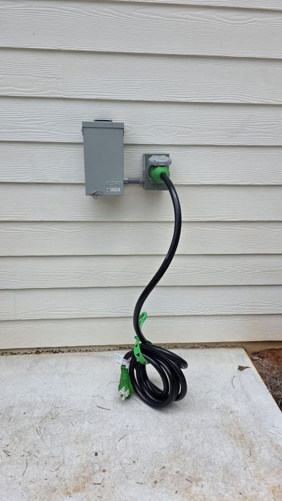 Exterior generator power inlet box with cord connected next to an Eaton disconnect on a Newnan, GA home, installed by Shocking Electric Solutions