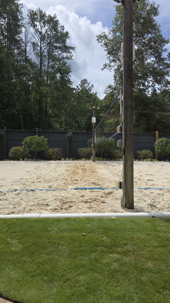 Wood pole with weatherproof outdoor receptacles and conduit at a backyard sand volleyball court in Fayetteville, GA, installed by Shocking Electric Solutions