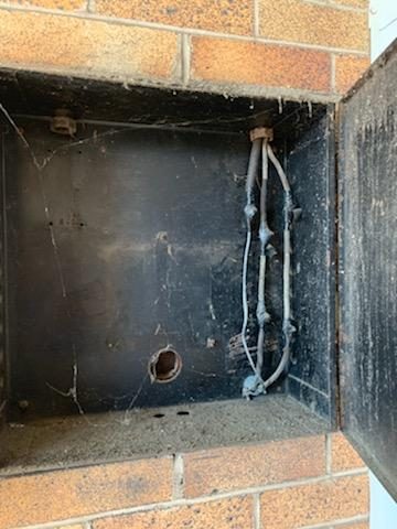 Rusted old fuse box enclosure with aging wiring set into a brick wall of a 1930s-era Newnan home