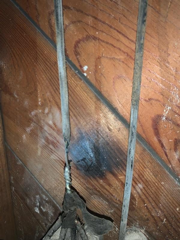 Old knob-and-tube wiring runs and a scorch mark on wood framing in a historic home rewired by Shocking Electric Solutions