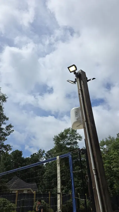 LED flood lights and conduit on a wood pole at a backyard sand volleyball court in Fayetteville, GA, installed by Shocking Electric Solutions
