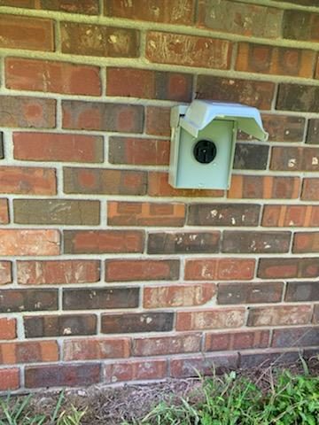 Outdoor RV and generator outlet with weatherproof cover on a brick home, installed by Shocking Electric Solutions