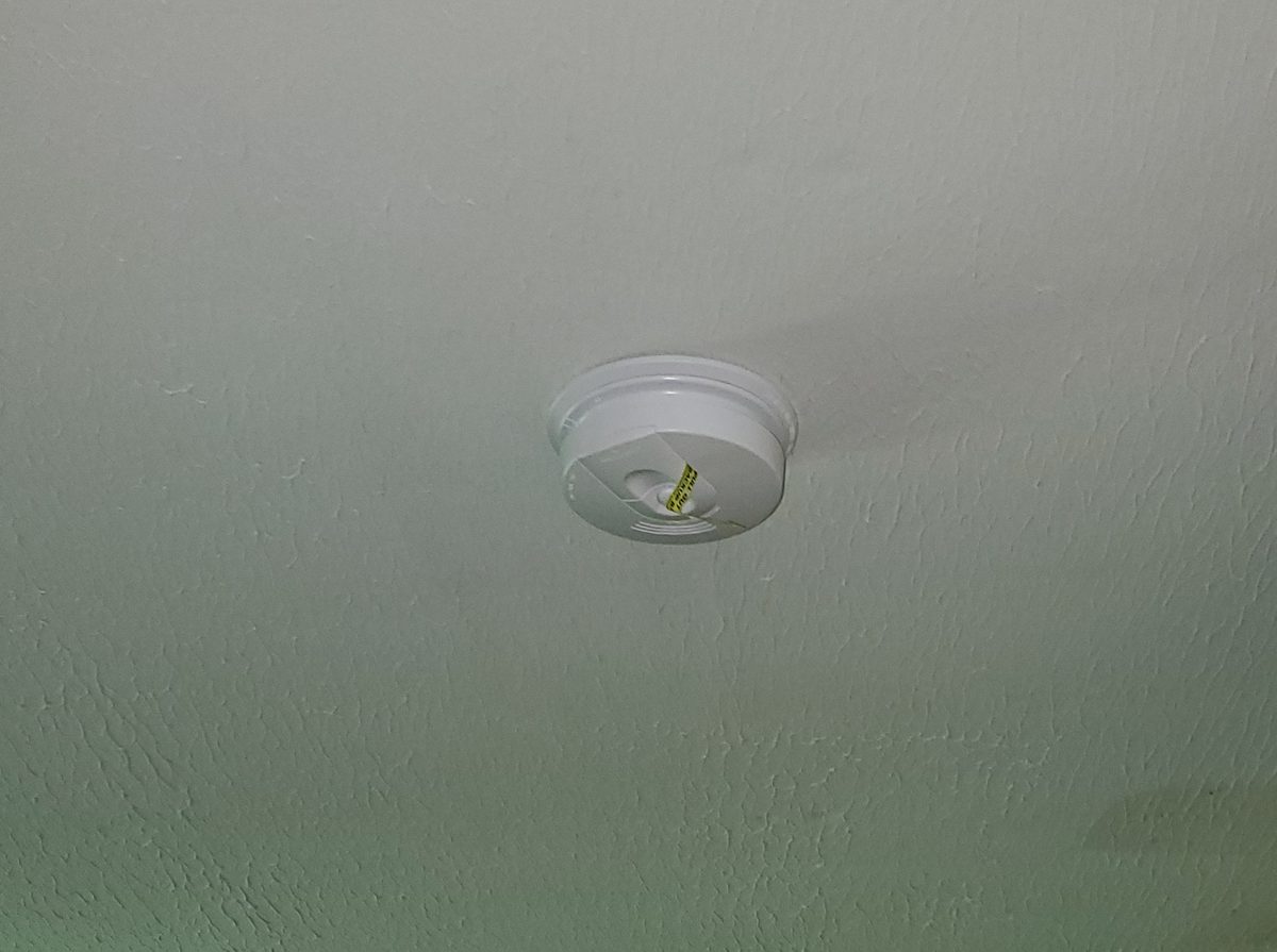 New hardwired smoke detector mounted on a textured ceiling away from corners and walls